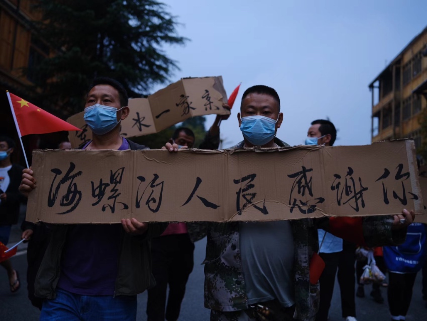 當?shù)厝罕娛謱懜兄x牌，歡送救援隊伍。程雪力攝