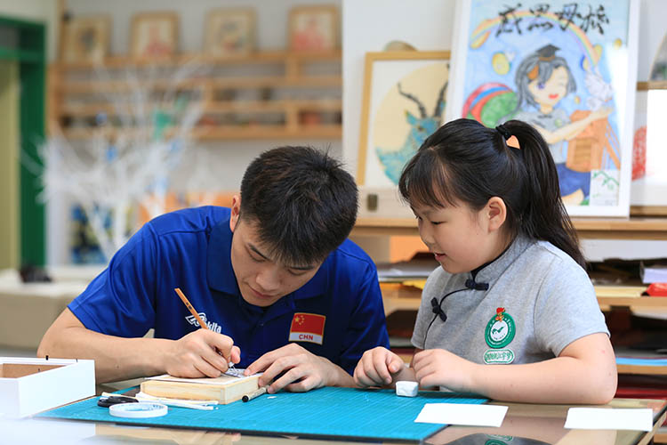 老師輔導(dǎo)學(xué)生剪紙。成都市草堂小學(xué)西區(qū)分校供圖